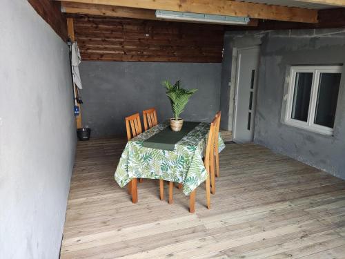 einen Tisch mit Stühlen und eine Topfpflanze auf einer Terrasse in der Unterkunft Studio plein pied in Hérin