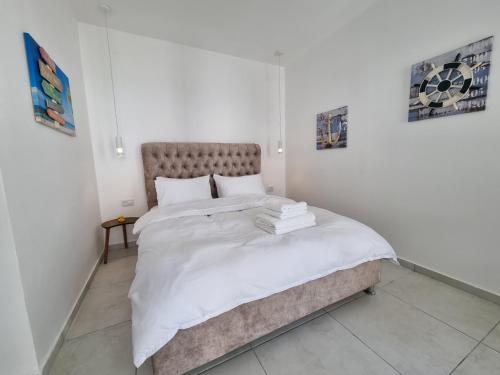 a white bedroom with a large bed with white sheets at Beachfront Achziv in Nahariyya