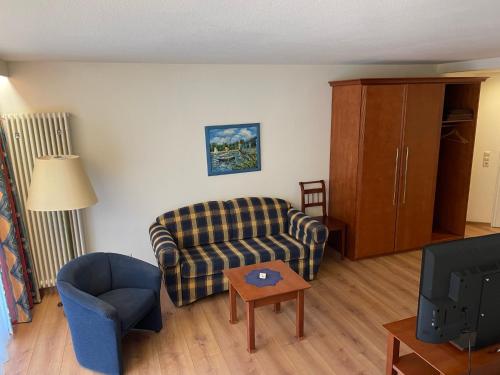 a living room with a couch and a chair and a tv at Moselromantik Hotel Am Panoramabogen in Cochem