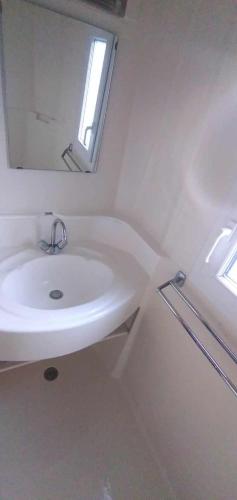 a white bathroom with a sink and a mirror at Chalet mobil-home in Pénestin