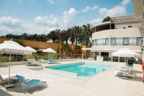 einen Pool mit Stühlen und Sonnenschirmen neben einem Gebäude in der Unterkunft Hotel Campestre Nala in Palmira