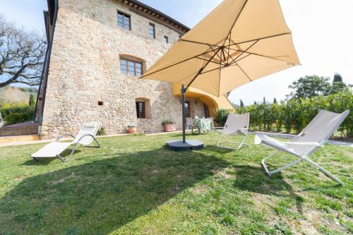 a group of chairs and an umbrella in a yard at Torre di Polvereto in Montespertoli