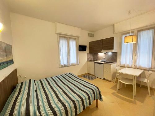 a bedroom with a bed and a table and a kitchen at Residence Glicini in Finale Ligure