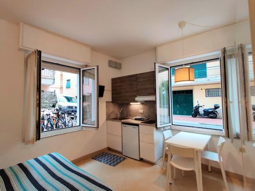 - une petite cuisine avec une table et 2 fenêtres dans l'établissement Residence Glicini, à Finale Ligure