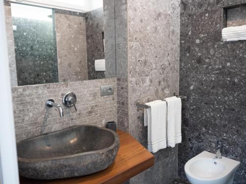 マッティナータにあるHotel Torre Santamaria Resortのバスルーム(大きな石の洗面台、トイレ付)