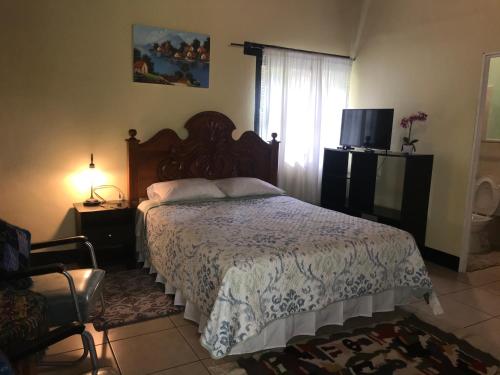 a bedroom with a bed and a television and a window at Villas JABEL TINAMIT in Panajachel