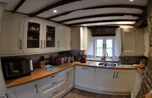 a kitchen with white cabinets and a sink at Pant Llwyd Farm in Llangynidr