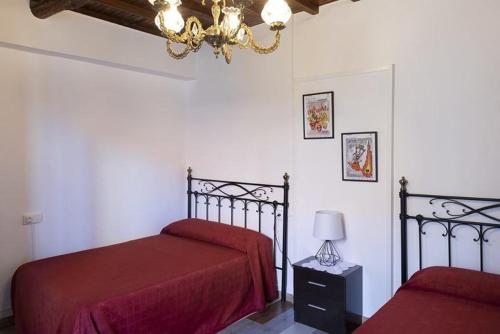 1 dormitorio con 2 camas con sábanas rojas y lámpara de araña en A Pousa Pensión rural (Camino de Santiago Sanabrés), en Armariz