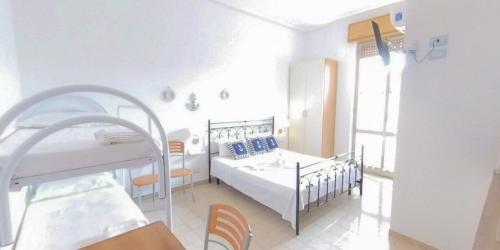 a white bedroom with two beds and a window at Stella Maris Marzamemi Apartments in Marzamemi