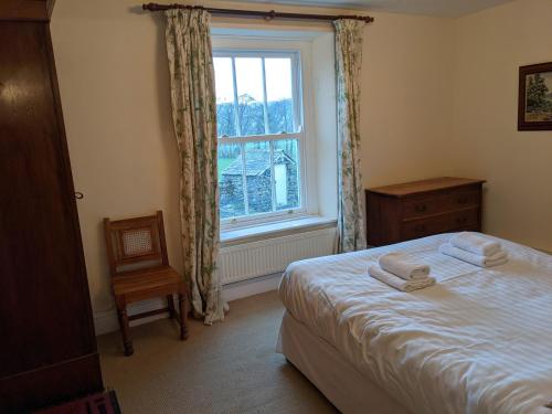 a bedroom with a bed and a window and a chair at Rose Cottage in Ulverston