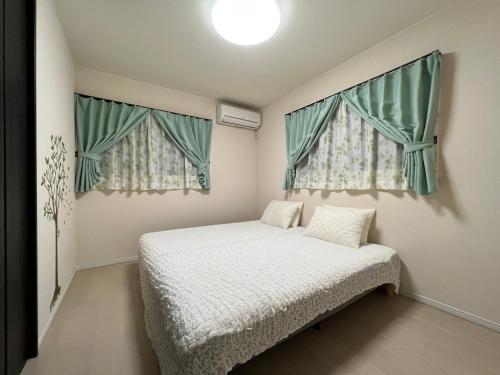Nara Guesthouse Kaede في نارا: غرفة نوم صغيرة بها سرير ونوافذ