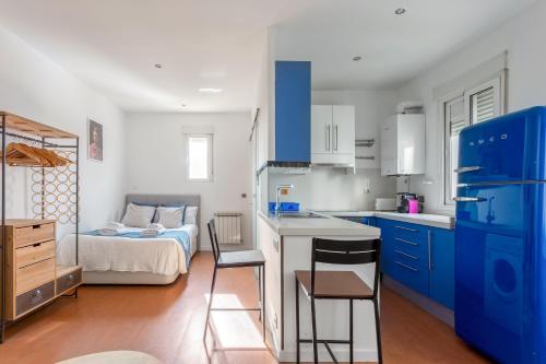 cocina con armarios azules y dormitorio con cama en Minty Stay - Hortaleza, en Madrid