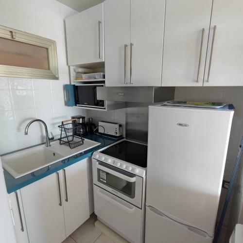 Elle comprend une petite cuisine avec des placards blancs et un réfrigérateur. dans l'établissement Grand studio bord de mer- accès direct aux plages, à Saint-Laurent-du-Var