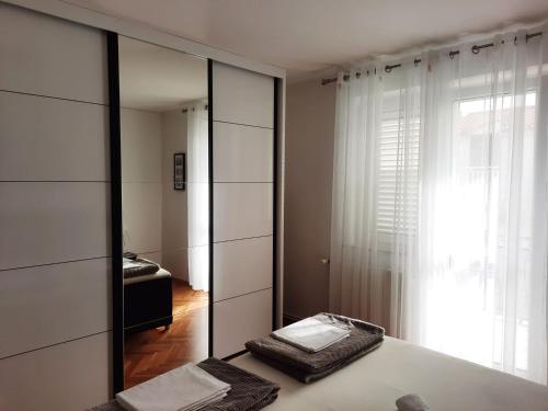 a bedroom with a mirror and a bed and a window at Apartments Rose Loboja in Makarska