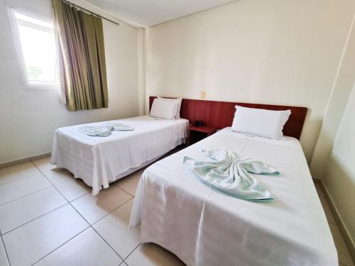 um quarto com duas camas com lençóis brancos em Cerrados Park Hotel em Várzea Grande