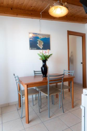 a dining room table with chairs and a vase with flowers at Stella Maris Marzamemi Apartments in Marzamemi