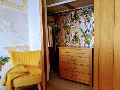 a closet with a yellow chair and a dresser at Panoramic sea views, sleeps 4, Torquay in Torquay