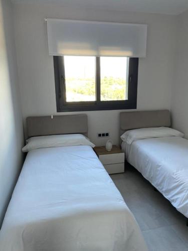 two beds in a room with a window at Sunset Waves Benidorm by Mar Holidays in Benidorm