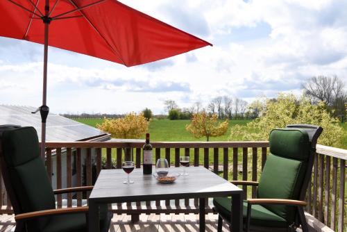 a table with a red umbrella and two glasses of wine at Die 5 Ferienwohnungen der Familie Weber in Fehmarn
