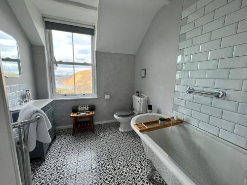 baño con bañera, aseo y ventana en Ty Capel, en Llanidloes