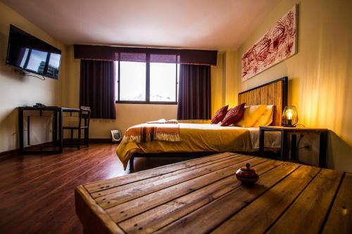 a bedroom with two beds and a wooden table at ISKAY BOUTIQUE HOSTEL in La Paz