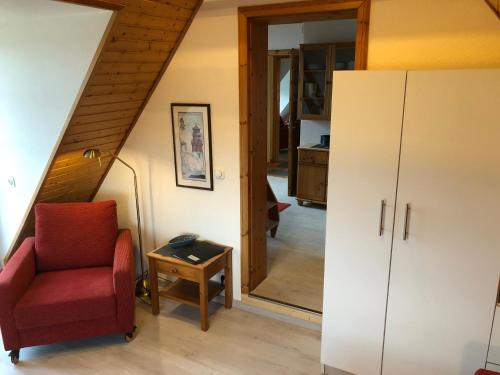 a living room with a red chair and a mirror at Die 5 Ferienwohnungen der Familie Weber in Fehmarn