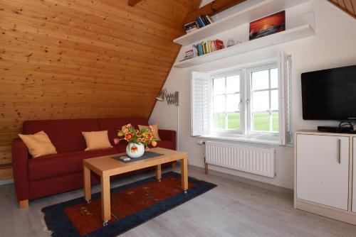 a living room with a red couch and a table at Die 5 Ferienwohnungen der Familie Weber in Fehmarn