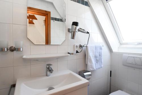 a white bathroom with a sink and a mirror at Die 5 Ferienwohnungen der Familie Weber in Fehmarn