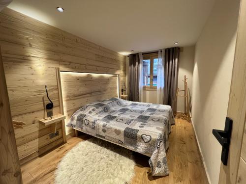 a bedroom with a bed with a wooden wall at BOREAL Bel appartement village et pistes in La Clusaz