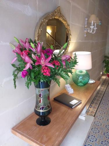 a vase of flowers on a table with a mirror at Central 214 Boutique Hotel in Hamrun