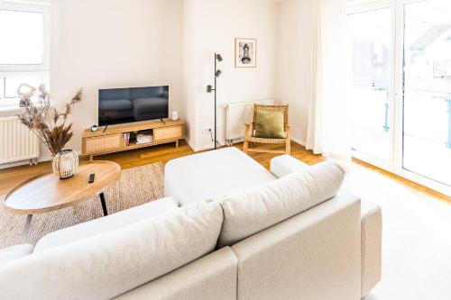 a white living room with a white couch and a table at Wunderschöne Ferienwohnung mit Feldblick und Balkon, mit kostenlosem Wlan und Strandfahrrad, Haustiere erlaubt in Börgerende-Rethwisch