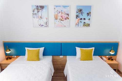 two beds in a room with blue and yellow pillows at La Playa Ha Long Hotel in Ha Long