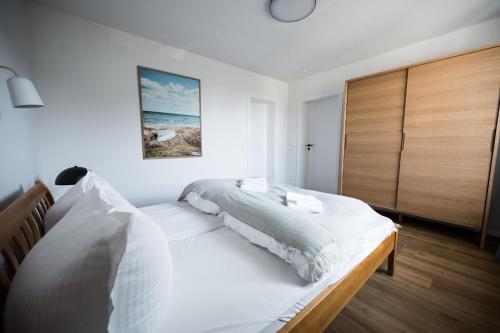 a bedroom with a large white bed with a wooden headboard at Wunderschöne Ferienwohnung mit Feldblick und Balkon (2022 renoviert), mit kostenlosem Wlan und Strandfahrrad, Haustiere erlaubt in Börgerende-Rethwisch