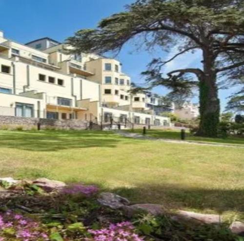 a large white building with a tree and some flowers at Panoramic sea views, sleeps 4, Torquay in Torquay