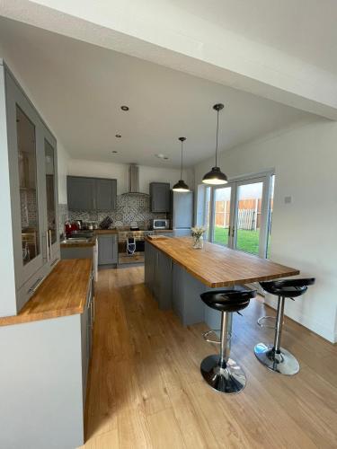 a large kitchen with a wooden counter and stools at Huge 6 Bedroom House in Sheringham in Sheringham