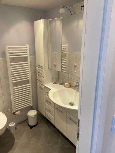 a white bathroom with a sink and a toilet at Top - Seaside Appartement mit Meerblick in Timmendorfer Strand