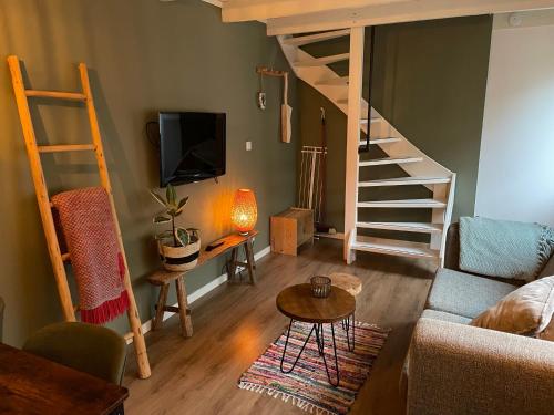 a living room with a couch and a tv and stairs at Beach House Parallel in Noordwijk