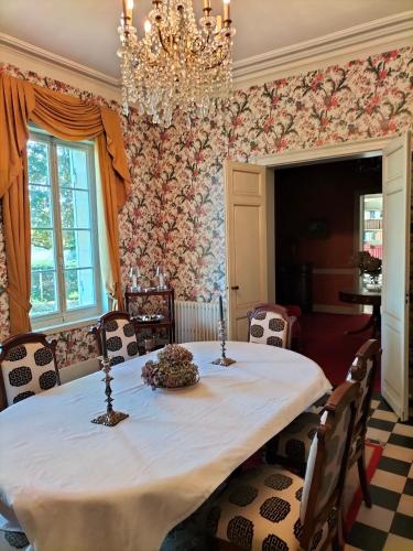 a dining room with a table and a chandelier at Château Le Baudou in Coutras
