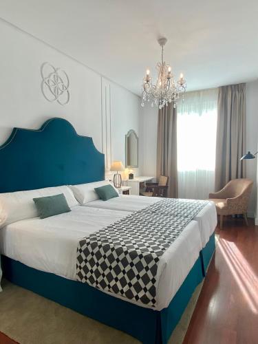 a bedroom with a large bed and a chandelier at Hotel Derby Sevilla in Seville