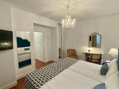 a bedroom with a large white bed and a chandelier at Hotel Derby Sevilla in Seville