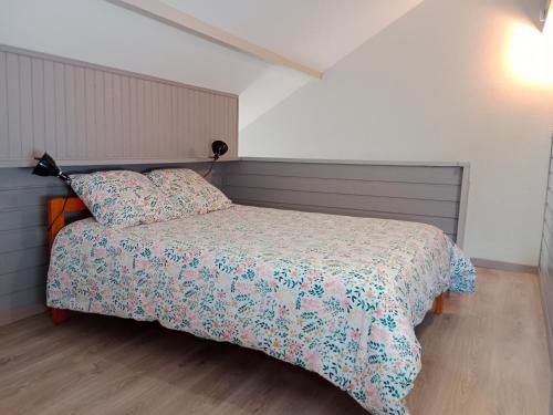 Gîte cosy Lac de Payolle في كامبان: غرفة نوم مع سرير مع لحاف متهالك
