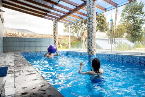 twee mensen spelen met een bal in een zwembad bij Tradicion Colca in Yanque