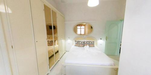 a white bedroom with a bed and a mirror at Stella Maris Marzamemi Apartments in Marzamemi