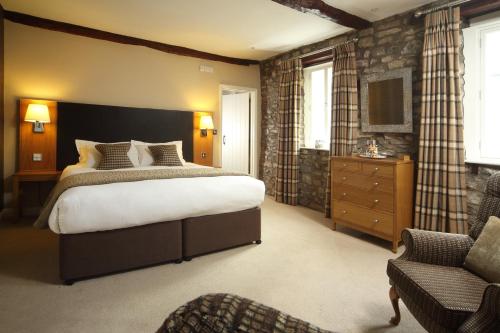 a bedroom with a large bed and a chair at Sun Inn in Kirkby Lonsdale