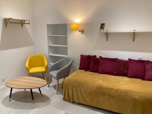 ein Schlafzimmer mit einem Bett, einem Stuhl und einem Tisch in der Unterkunft Appart' Au Coeur de Nuits in Nuits-Saint-Georges