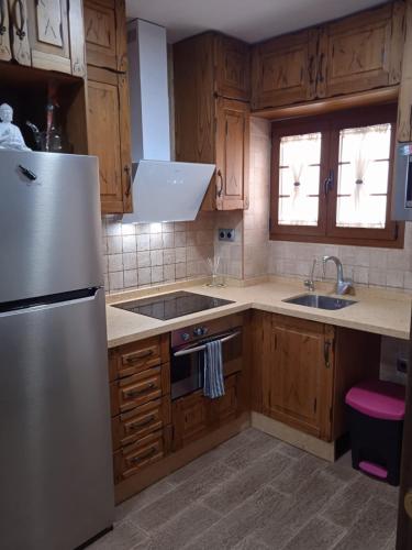 a kitchen with wooden cabinets and a white refrigerator at El Cuchitril in Almería
