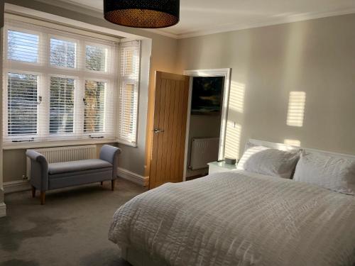 a bedroom with a bed and a chair and windows at Stunning 2 Bed Georgian Apartment in Swafield