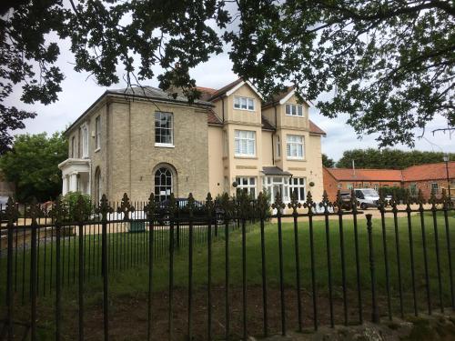 a large house behind a wrought iron fence at Stunning 2 Bed Georgian Apartment in North Walsham