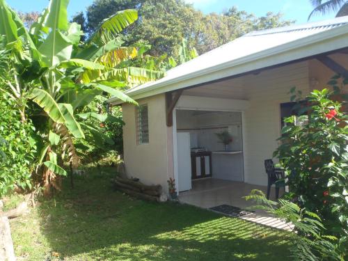 a small white house with a porch in a yard at GITE LOCA in Capesterre