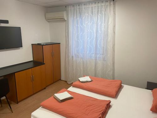 two beds in a room with a tv and a bedskirts at Room AA in Dravograd